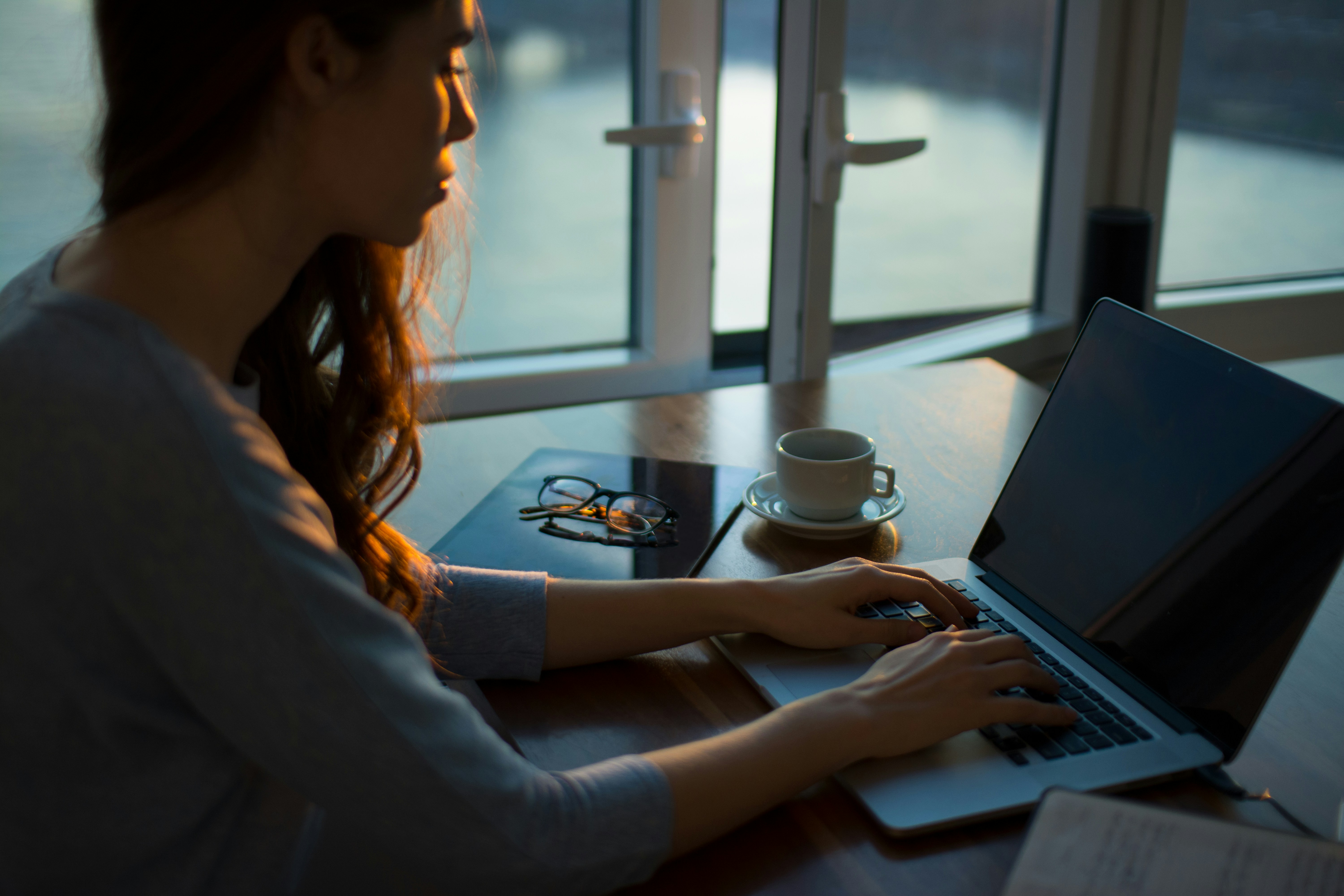 A woman works at her desk, typing on a laptop. 